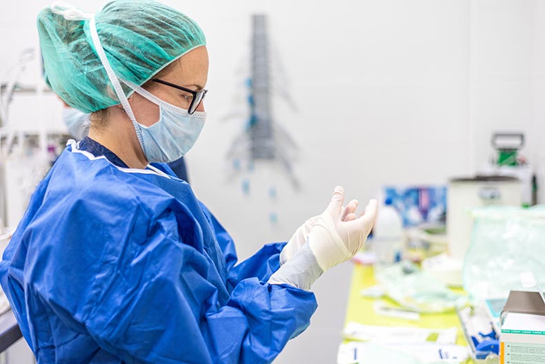 Photo of healthcare worker in PPE looking at a sample in a lab