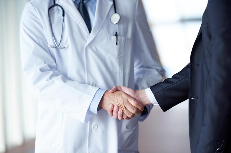 Photo of doctor shaking hands with a person in a suit